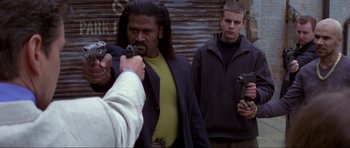 Movie still from “The World Is Not Enough” (1999), directed by Michael Apted – A group of men standing next to each other holding guns; Medium shot, Over the shoulder angle