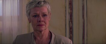 Movie still from “The World Is Not Enough” (1999), directed by Michael Apted – An older woman with short grey hair looking at the camera; Close Up shot, Low angle