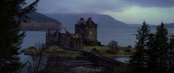 Movie still from “The World Is Not Enough” (1999), directed by Michael Apted – A castle on the shore of a body of water; Extreme Wide shot, Low angle
