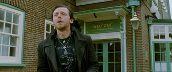 Movie still from “The World's End” (2013), directed by Edgar Wright – A man standing in front of a building with a welcome sign; Close Up shot, Over the shoulder angle