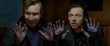 Movie still from “The World's End” (2013), directed by Edgar Wright – Two men are holding their hands up in front of each other; Medium shot, High angle