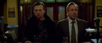 Movie still from “The World's End” (2013), directed by Edgar Wright – Two men are sitting at a table with drinks in front of them; Medium shot, Low angle