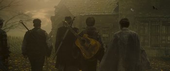 Movie still from “The World's End” (2013), directed by Edgar Wright – A group of people walking down a street with a guitar; Medium shot, Low angle