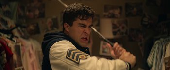 Movie still from “There's Someone Inside Your House” (2021), directed by Patrick Brice – A man holding a knife in his mouth; Close Up shot, Over the shoulder angle