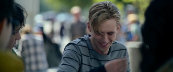 Movie still from “There's Someone Inside Your House” (2021), directed by Patrick Brice – A young man smiles while looking at his cell phone; Close Up shot, Over the shoulder angle