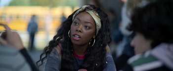 Movie still from “There's Someone Inside Your House” (2021), directed by Patrick Brice – A woman with long black hair wearing a head scarf; Close Up shot, Over the shoulder angle