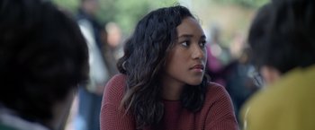 Movie still from “There's Someone Inside Your House” (2021), directed by Patrick Brice – A woman with long black curly hair looking to her left; Close Up shot, Over the shoulder angle