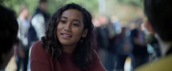 Movie still from “There's Someone Inside Your House” (2021), directed by Patrick Brice – A young woman with long black hair wearing a red sweater; Close Up shot, Over the shoulder angle