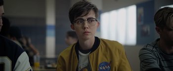 Movie still from “There's Someone Inside Your House” (2021), directed by Patrick Brice – A young man wearing glasses and a yellow jacket; Close Up shot, Over the shoulder angle