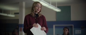 Movie still from “There's Someone Inside Your House” (2021), directed by Patrick Brice – A young woman holding a piece of paper in her hands; Close Up shot, Over the shoulder angle