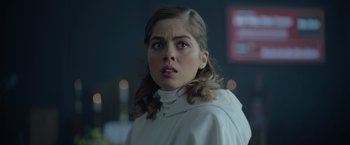 Movie still from “There's Someone Inside Your House” (2021), directed by Patrick Brice – A young woman in a white jacket looking at the camera; Close Up shot, Over the shoulder angle