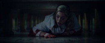 Movie still from “There's Someone Inside Your House” (2021), directed by Patrick Brice – A woman laying on the ground with blood all over her face; Close Up shot, Overhead angle