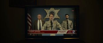 Movie still from “There's Someone Inside Your House” (2021), directed by Patrick Brice – A television screen showing a news story about a sheriff's office; Close Up shot, Low angle