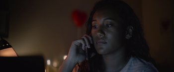 Movie still from “There's Someone Inside Your House” (2021), directed by Patrick Brice – A woman is talking on a cell phone; Close Up shot, Low angle