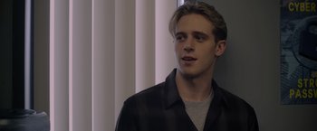 Movie still from “There's Someone Inside Your House” (2021), directed by Patrick Brice – A young man in a black shirt is looking to his left; Close Up shot, Over the shoulder angle