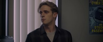Movie still from “There's Someone Inside Your House” (2021), directed by Patrick Brice – A young man in a black and white shirt looks to his left; Close Up shot, Low angle