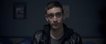 Movie still from “There's Someone Inside Your House” (2021), directed by Patrick Brice – A young man wearing a black leather jacket; Close Up shot, Over the shoulder angle