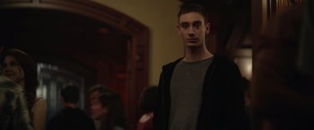 Movie still from “There's Someone Inside Your House” (2021), directed by Patrick Brice – A young man standing in front of a group of people; Medium shot, Low angle