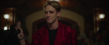 Movie still from “There's Someone Inside Your House” (2021), directed by Patrick Brice – A young man in a red jacket is smiling for the camera; Close Up shot, Over the shoulder angle