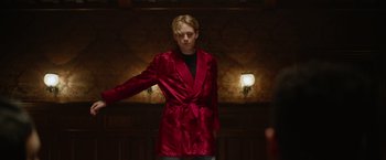 Movie still from “There's Someone Inside Your House” (2021), directed by Patrick Brice – A man in a red robe standing next to a light; Medium shot, Low angle