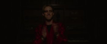 Movie still from “There's Someone Inside Your House” (2021), directed by Patrick Brice – A young man in a red robe is smiling; Medium shot, Over the shoulder angle
