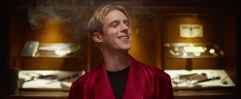 Movie still from “There's Someone Inside Your House” (2021), directed by Patrick Brice – A young man in a red robe is smiling; Close Up shot, Low angle