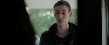 Movie still from “There's Someone Inside Your House” (2021), directed by Patrick Brice – A young man in a black jacket looking at the camera; Close Up shot, Over the shoulder angle