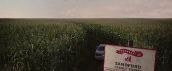 Movie still from “There's Someone Inside Your House” (2021), directed by Patrick Brice – A car parked in the middle of a corn field; Extreme Wide shot, High angle