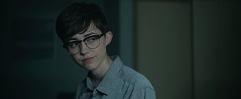 Movie still from “There's Someone Inside Your House” (2021), directed by Patrick Brice – A young man wearing glasses and a gray shirt; Close Up shot, Over the shoulder angle