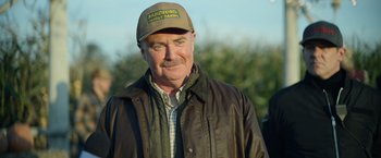 Movie still from “There's Someone Inside Your House” (2021), directed by Patrick Brice – An older man wearing a hat and a jacket; Close Up shot, Over the shoulder angle