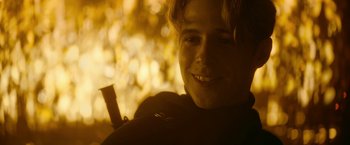 Movie still from “There's Someone Inside Your House” (2021), directed by Patrick Brice – A young man smiling for the camera in front of a tree; Close Up shot, Over the shoulder angle