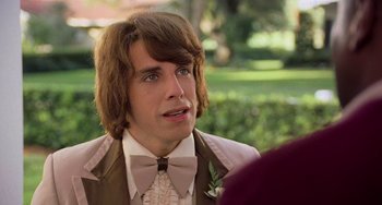 Movie still from “There's Something About Mary” (1998), directed by Bobby Farrelly – A man with long brown hair wearing a bow tie; Close Up shot, Over the shoulder angle