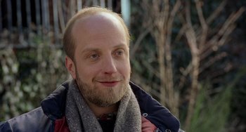 Movie still from “There's Something About Mary” (1998), directed by Bobby Farrelly – A person with a beard wearing a scarf; Close Up shot, Over the shoulder angle