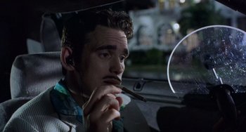 Movie still from “There's Something About Mary” (1998), directed by Bobby Farrelly – A man sitting in the driver's seat of a car while smoking a cigarette; Close Up shot, Over the shoulder angle