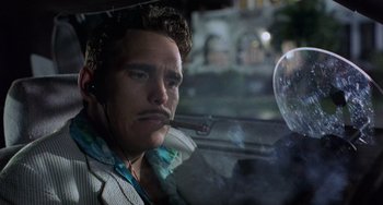 Movie still from “There's Something About Mary” (1998), directed by Bobby Farrelly – A man sitting in the back seat of a car; Close Up shot, Low angle