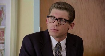 Movie still from “There's Something About Mary” (1998), directed by Bobby Farrelly – A man in a suit and tie wearing glasses; Close Up shot, Low angle