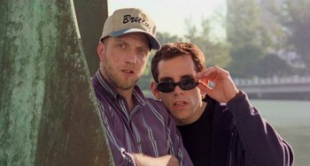Movie still from “There's Something About Mary” (1998), directed by Bobby Farrelly – A couple of men standing next to each other near a tree; Close Up shot, Low angle