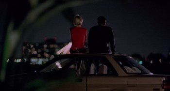 Movie still from “There's Something About Mary” (1998), directed by Bobby Farrelly – A man and a woman sitting on the back of a car; Wide shot, High angle