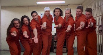 Movie still from “There's Something About Mary” (1998), directed by Bobby Farrelly – A group of men in red jumpsuits posing for a picture; Medium shot, Low angle
