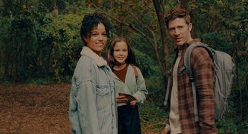 Movie still from “There's Something Wrong with the Children” (2023), directed by Roxanne Benjamin – A group of people standing next to each other in the woods; Medium shot, High angle