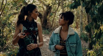 Movie still from “There's Something Wrong with the Children” (2023), directed by Roxanne Benjamin – Two young women standing next to each other in a wooded area; Medium shot, Over the shoulder angle