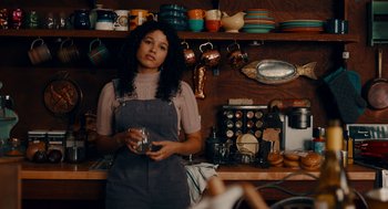 Movie still from “There's Something Wrong with the Children” (2023), directed by Roxanne Benjamin – A woman standing in front of a wall of dishes; Medium shot, Low angle