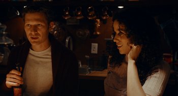 Movie still from “There's Something Wrong with the Children” (2023), directed by Roxanne Benjamin – A man and a woman are standing in a kitchen; Medium shot, Over the shoulder angle