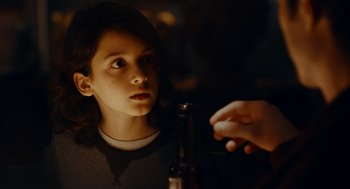 Movie still from “There's Something Wrong with the Children” (2023), directed by Roxanne Benjamin – A young boy is looking at a bottle of beer; Close Up shot, Over the shoulder angle
