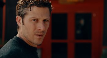 Movie still from “There's Something Wrong with the Children” (2023), directed by Roxanne Benjamin – A man's face in front of a red door; Close Up shot, Low angle