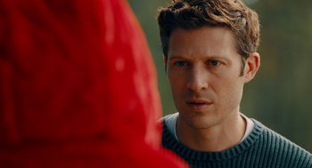 Movie still from “There's Something Wrong with the Children” (2023), directed by Roxanne Benjamin – A person wearing a sweater looking at the camera; Close Up shot, Over the shoulder angle