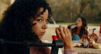 Movie still from “There's Something Wrong with the Children” (2023), directed by Roxanne Benjamin – A woman sitting at a table in a park; Close Up shot, Over the shoulder angle