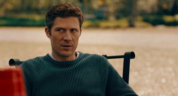 Movie still from “There's Something Wrong with the Children” (2023), directed by Roxanne Benjamin – A person sitting on a chair; Close Up shot, Over the shoulder angle