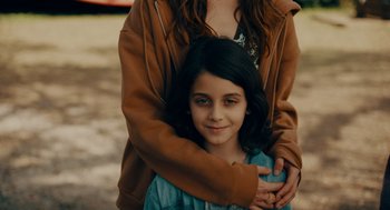 Movie still from “There's Something Wrong with the Children” (2023), directed by Roxanne Benjamin – A woman hugging a little girl in a blue dress; Close Up shot, High angle