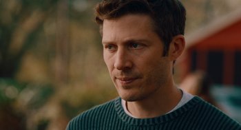 Movie still from “There's Something Wrong with the Children” (2023), directed by Roxanne Benjamin – A person wearing a green sweater; Close Up shot, Over the shoulder angle